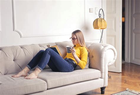Mujer Sentada En El Sofá Blanco Mientras Lee Un Libro · Fotos De Stock