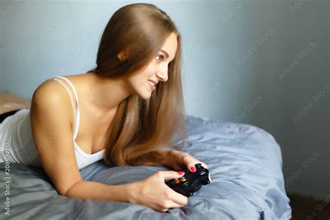 Girl Gamer Plays With A Wireless Gamepad While Looking At The Screen In
