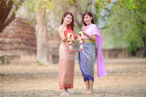 attractive thai women in traditional thai dress hold fresh flower garlands for entering a temple