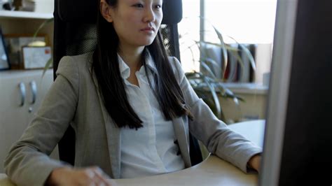 Tilt Up Shot Of Young Asian Woman In Formal Clothes Sitting At Desk In