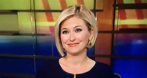 A Woman In A Black Dress Is Smiling For The Camera While Sitting On A News Set