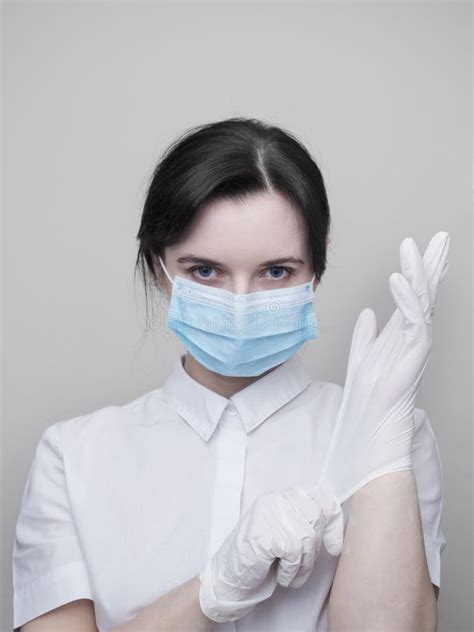 Young Woman Patient In A Medical Mask Puts On Protective Surgical