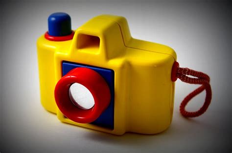 A Yellow Toy Camera Sitting On Top Of A White Table Next To A Red Cord