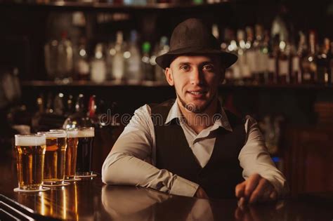 Happy Bearded Bartender At Bar Counter With Glasses Of Beer Stock Photo