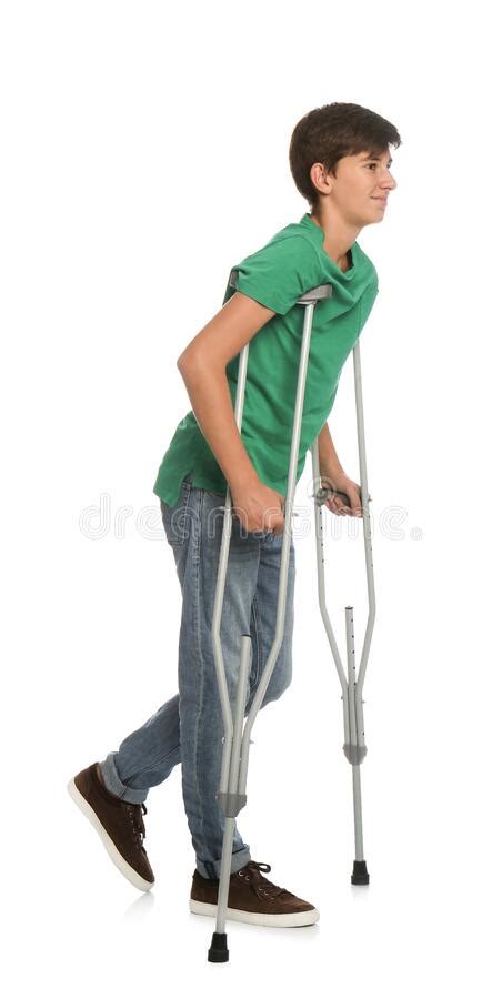 Teenage Boy With Injured Leg Using Crutches On Yellow Background Space