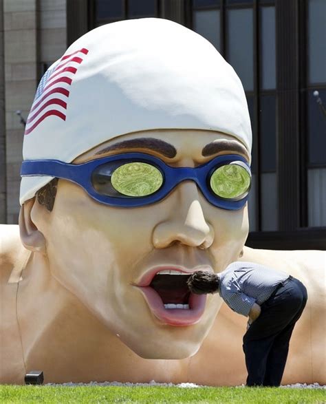 An Undentified Man Peers Into The Mouth Of A Giant Sculpture Of A Swimmer In Front Of The Mutual