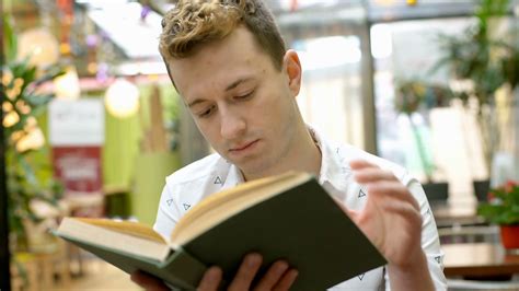 Handsome Man Reading Book In The Cafe And Looking To The Camera Stock Video Footage Storyblocks
