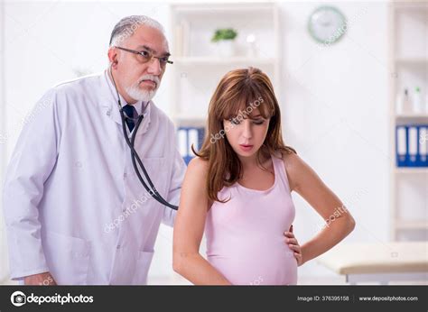 Молодая беременная женщина посещает пожилого врача гинеколога
