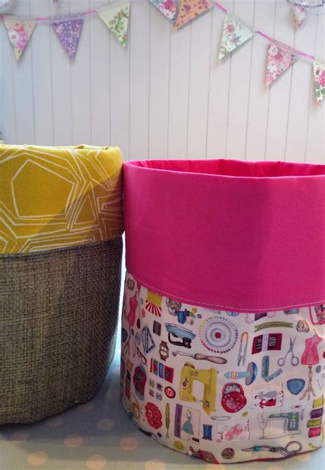 Two Fabric Storage Baskets Sitting Next To Each Other On Top Of A White