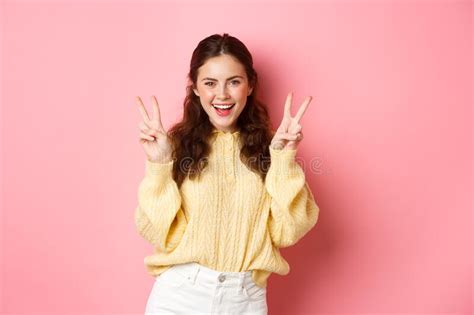 Portrait Of Attractive Brunette Female Model Smiling And Showing Peace Signs Making V Sign