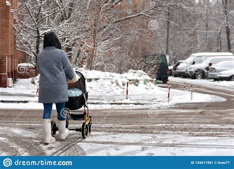 A Woman With A Stroller And A Child Goes Into Heavy Snow Walk With The