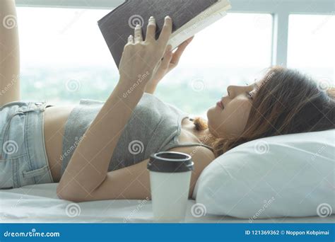 Young Woman Reading Book On Bed At Home In The Morning With Coffee Cup Girl Enjoying Novel In