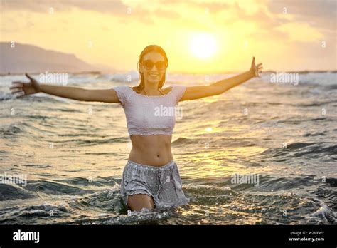 Young Lively Teenage Woman With Open Arms In Sea Water At Beach Wet
