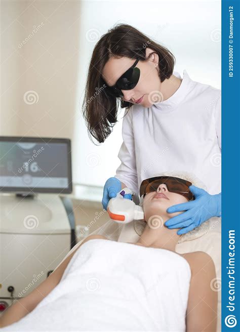 Professional Cosmetologist Treating Human Skin With Laser While Touching Of Female Face With