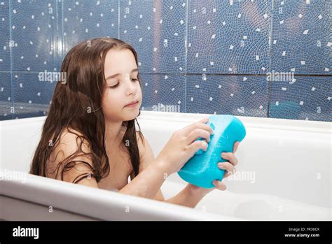 Little Smiling Girl With Long Brown Hair Taking A Bath With A Blue