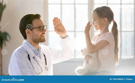 Friendly Male Pediatrician Giving High Five To Little Patient Stock