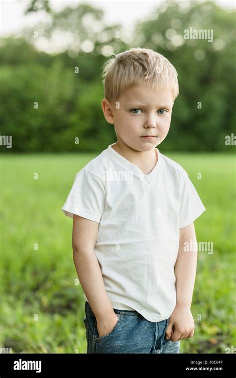 Portrait Of Cute Boy Standing With Hand In Pocket On Field Stock Photo