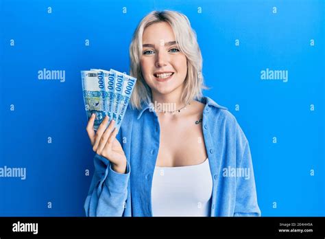 Young Blonde Girl Holding Hungarian Forint Banknotes Looking Positive And Happy Standing And