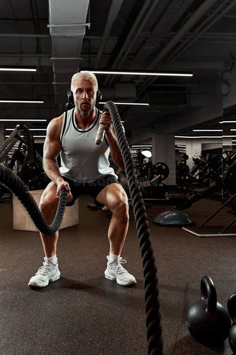 Sport Strong Man Exercising With Battle Ropes At The Gym With Athlete