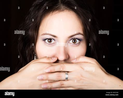 Close Up Woman Looks Straight Into The Camera On A Black Background She Covered Her Mouth With