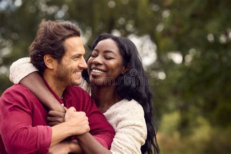 Loving Mixed Race Couple Leaning On Fence On Walk In Countryside Stock