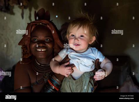 Himba Woman Holding A White Tourist Baby Kaokoland Namibia Stock
