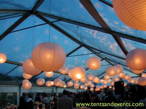 White Paper Lanterns With Amber Light Bulbs In A Clear Top Tent At Dusk