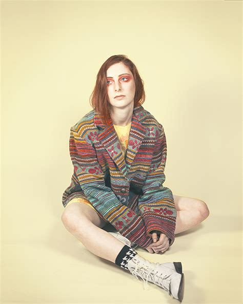 Girl In Colored Sweater Sits Cross Legged Pale Yellow Background