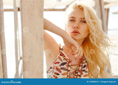 Blonde With Curly Hairblue Eyesbig Lips Supported On A Wooden