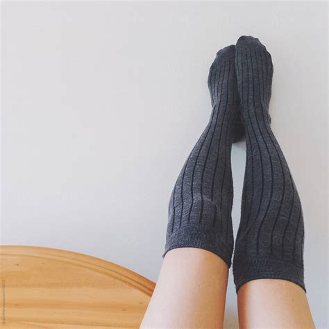 Woman Wearing Long Grey Socks Rests Her Feet On A Wall By Stocksy