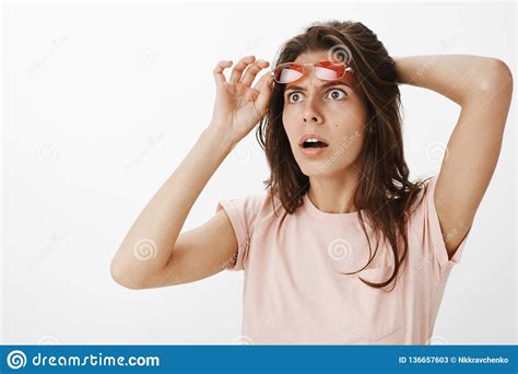 shocked and surprised stunned attractive woman witnessing ufo in sky taking of red sunglasses