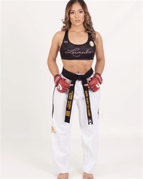 A Woman In Black Top And White Pants With Boxing Gloves On Her Hip