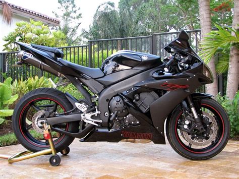 A Black Motorcycle Parked On Top Of A Wooden Floor Next To Trees And