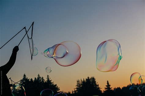 Person Playing With Large Soap Bubbles At Sunset By Stocksy Contributor Carolyn Lagattuta