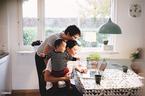Lesbian Couple With Daughter Looking In Laptop At Kitchen Photo Getty