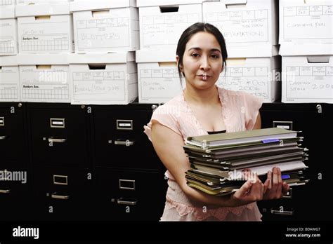 Portrait Of A File Clerk Holding A Stack Of Files In Front Of A Filing