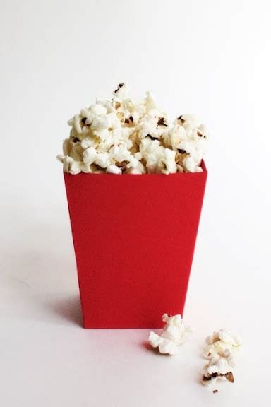 A Red Box Filled With Popcorn Sitting On Top Of A White Table