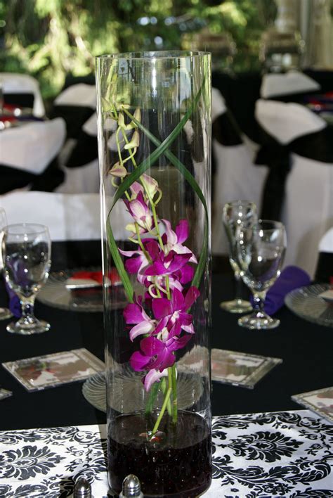 One Of Our Most Popular Centerpieces For Weddings A Cylinder Vase Encased With Orchids Lily