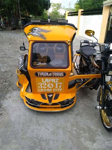 An Orange Three Wheeled Vehicle Parked Next To A Motorcycle