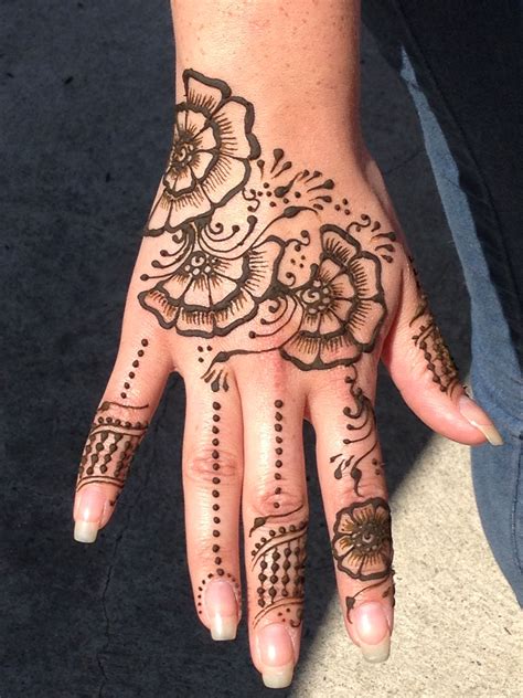 a woman s hand with henna tattoos and flowers on the palm which is decorated