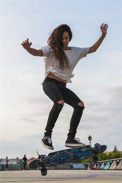 Young Woman Doing A Skateboard Trick In The City Stock Photo