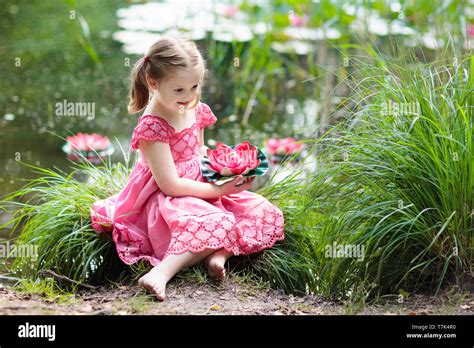 Child Sitting At Lake Shore Watching Water Lily Flowers