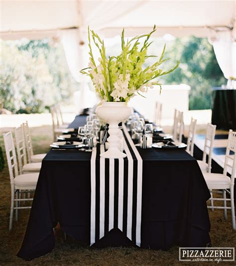 A Black And White Table Cloth With Flowers In A Vase On Top Is Set Up