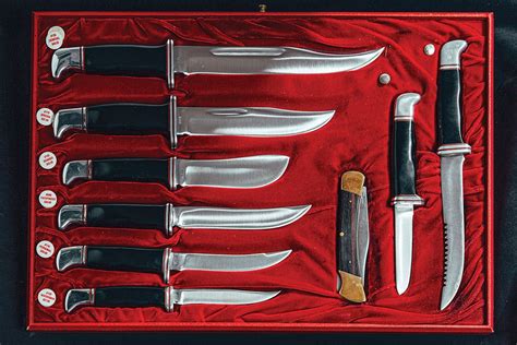 An Assortment Of Knives Are Displayed In A Red Box With Black Trimmings