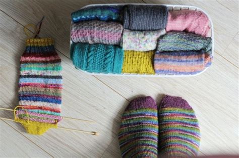 There Are Several Pairs Of Knitted Slippers Next To A Pair Of Knitting Needles