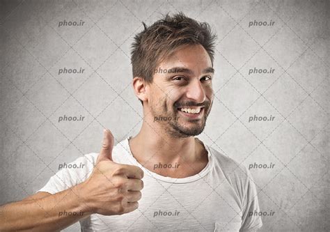 عکس با کیفیت مرد با لبخند در حال نشان دادن شست دست به معنای تأیید عکس با کیفیت و تصاویر استوک