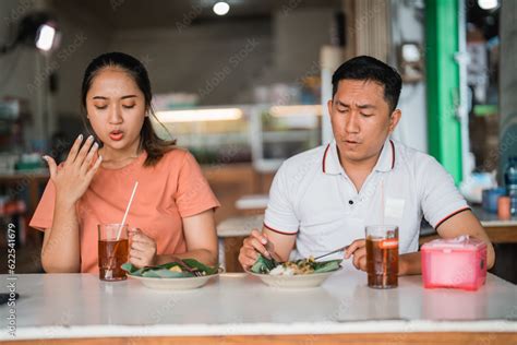 Asian Woman And Man Sitting With A Spicy Expression While Eating Pecel