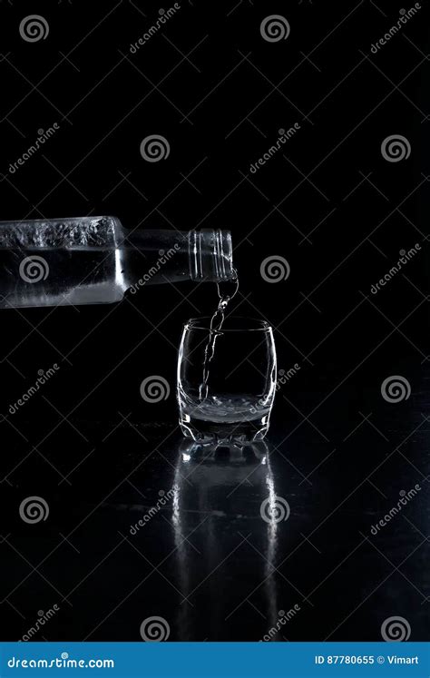 Bottle Vodka Poured Into A Glass On Black Background Stock Image