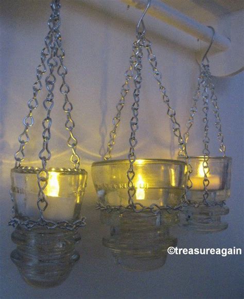 Three Hanging Glass Jars Filled With Candles On A Hook And Chain