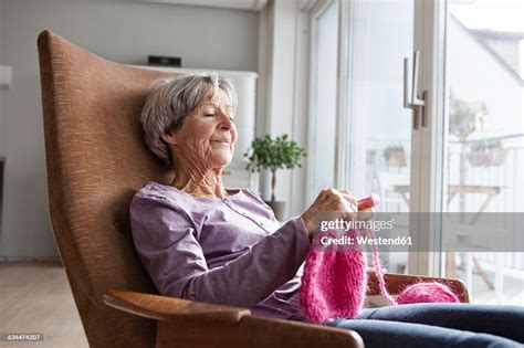 Portrait Of Senior Woman Sitting On Armchair At Home Knitting Photo